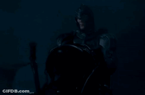 A Man In A Knight 'S Armor Is Holding A Sword In The Dark . GIF