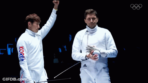 A Man In A Korea Shirt Holds His Fist Up In The Air GIF