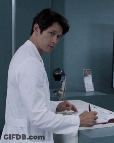 A Man In A Lab Coat Is Standing In Front Of A Counter GIF