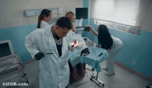 A Man In A Lab Coat Is Standing Next To A Woman In A Hospital Bed With A Sign That Says Sabrosa GIF