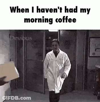 A Man In A Lab Coat Is Walking Down A Hallway With A Box In His Hand . GIF