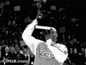 A Man In A Lakers Jersey Holds Up A Trophy In Front Of A Crowd GIF