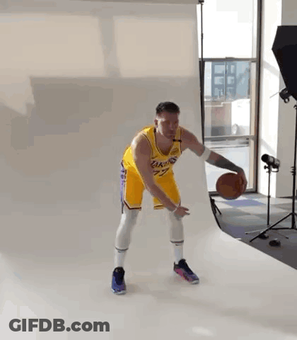 A Man In A Lakers Jersey Is Holding A Basketball In A Studio . GIF