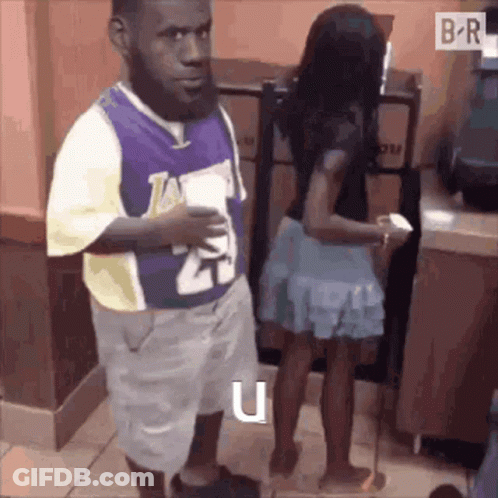 A Man In A Lakers Jersey Is Standing Next To A Woman . GIF