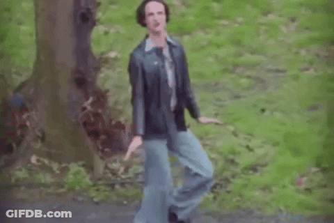 A Man In A Leather Jacket And Blue Jeans Is Dancing In The Woods . GIF