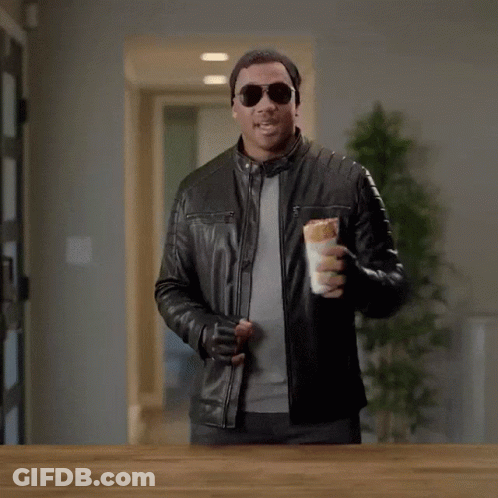A Man In A Leather Jacket Holding A Sandwich With The Words " Here Comes The Airplane " On The Bottom GIF