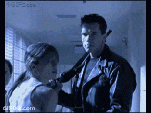 A Man In A Leather Jacket Holds A Gun To A Woman 'S Neck And Says 4Gifs.com At The Bottom GIF