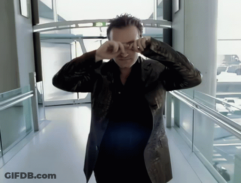 A Man In A Leather Jacket Is Covering His Eyes With His Hands GIF