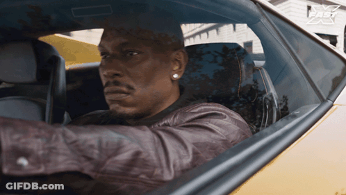 A Man In A Leather Jacket Is Driving A Car With A Fast Logo On The Side GIF