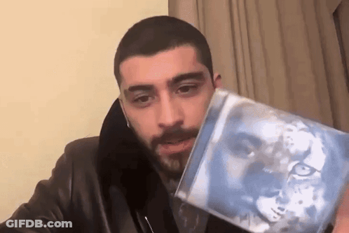 A Man In A Leather Jacket Is Holding A Cd With A Picture Of A Lion On It . GIF