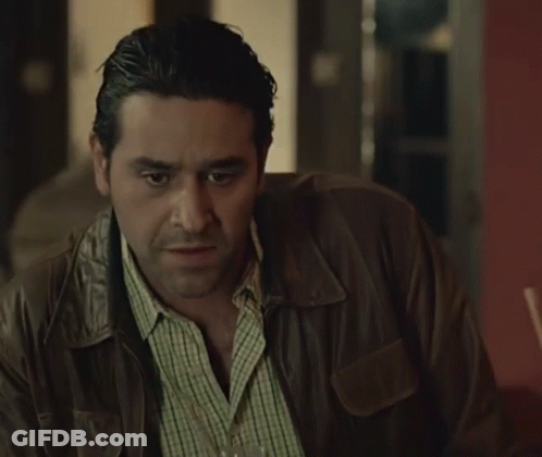 A Man In A Leather Jacket Is Holding A Glass Of Wine GIF