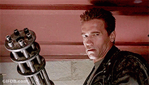 A Man In A Leather Jacket Is Holding A Gun GIF