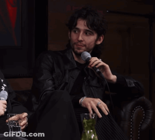 A Man In A Leather Jacket Is Holding A Microphone GIF