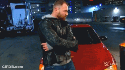 A Man In A Leather Jacket Is Hugging A Red Car In Front Of A Fire Barrel That Says WWE Live GIF