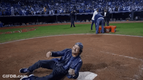 A Man In A Leather Jacket Is Laying On The Ground On A Baseball Field GIF