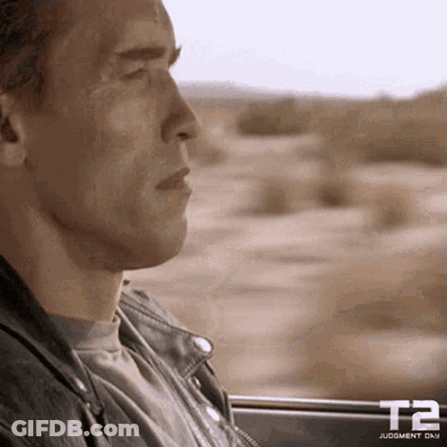 A Man In A Leather Jacket Is Looking Out Of A Car Window GIF