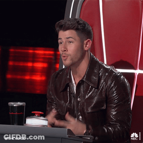 A Man In A Leather Jacket Is Sitting At A Desk With A Nbc Logo On The Bottom GIF