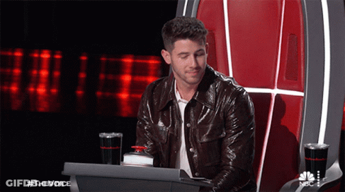 A Man In A Leather Jacket Is Sitting In A Chair With A Laptop In Front Of Him And The Words #Thevoice On The Bottom GIF