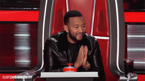 A Man In A Leather Jacket Is Sitting In A Chair With The Word The Voice On The Back GIF