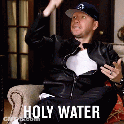A Man In A Leather Jacket Is Sitting In A Chair With The Words Holy Water On The Bottom GIF