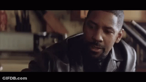 A Man In A Leather Jacket Is Sitting In A Room Talking To Another Man . GIF