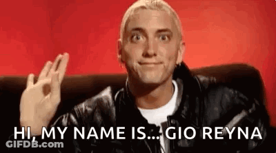 A Man In A Leather Jacket Is Sitting On A Couch And Making An Ok Sign . GIF