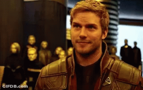 A Man In A Leather Jacket Is Smiling In Front Of A Group Of People . GIF