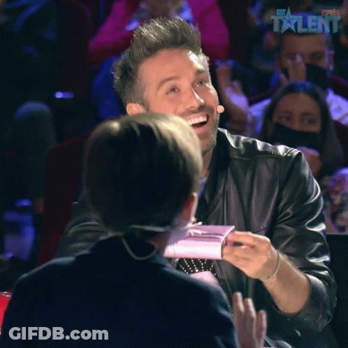 A Man In A Leather Jacket Is Smiling In Front Of A Sign That Says ' Estrella Talent ' GIF