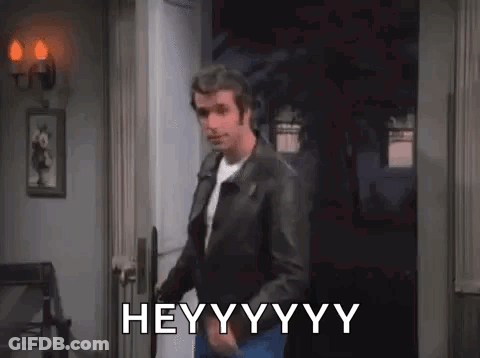 A Man In A Leather Jacket Is Standing In A Doorway And Says Hey . GIF