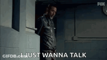 A Man In A Leather Jacket Is Standing In A Doorway And Talking . GIF