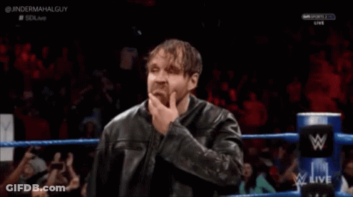 A Man In A Leather Jacket Is Standing In A Wrestling Ring With His Hand To His Chin . GIF