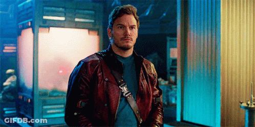 A Man In A Leather Jacket Is Standing In Front Of A Building . GIF