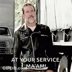 A Man In A Leather Jacket Is Standing In Front Of A Truck With The Words `` At Your Service , Ma 'Am '' . GIF