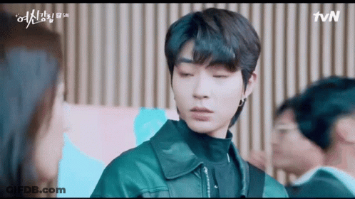 A Man In A Leather Jacket Is Standing In Front Of A Woman In A Room . GIF