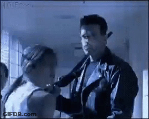 A Man In A Leather Jacket Is Talking To A Woman In A White Tank Top GIF