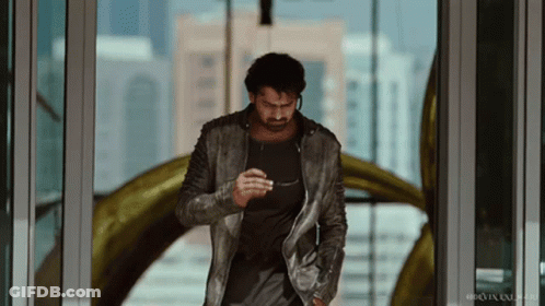 A Man In A Leather Jacket Is Walking Through A Door GIF