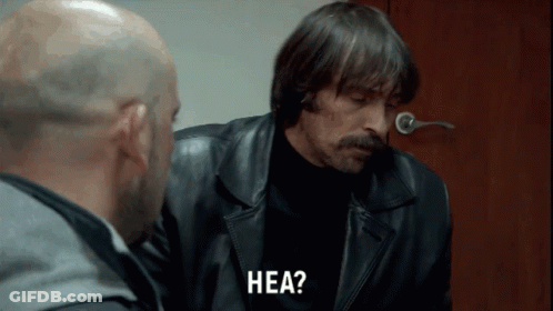 A Man In A Leather Jacket Says Hea While Talking To Another Man GIF