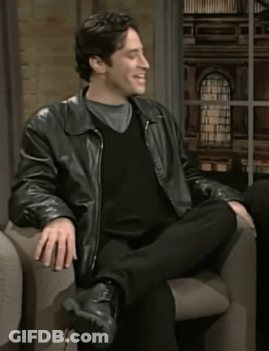 A Man In A Leather Jacket Sits In A Chair GIF
