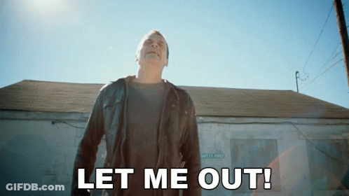 A Man In A Leather Jacket Stands In Front Of A Building With The Words Let Me Out GIF