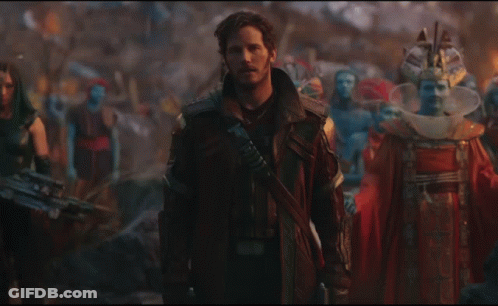 A Man In A Leather Jacket Stands In Front Of A Crowd Of People GIF