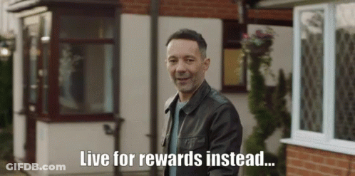 A Man In A Leather Jacket Stands In Front Of A House With The Words Live For Rewards Instead Written Below Him GIF