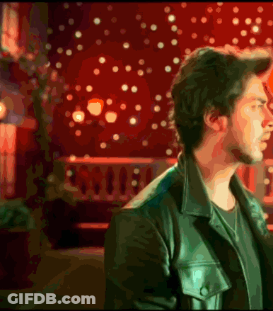 A Man In A Leather Jacket Stands In Front Of A Red Background GIF