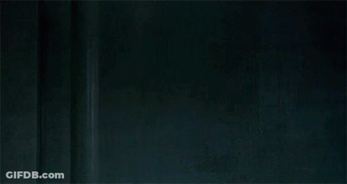 A Man In A Leather Jacket With A Bloody Face Is Standing Next To A Wall . GIF