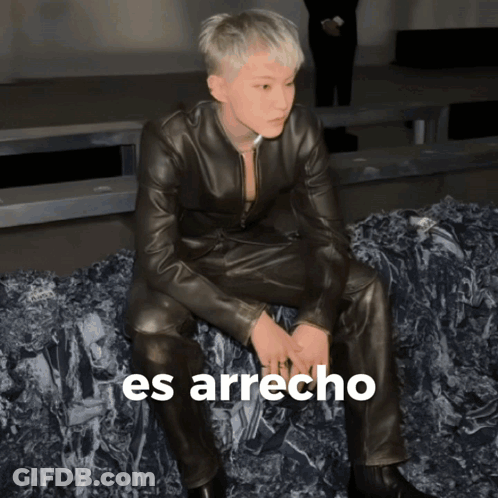 A Man In A Leather Suit Is Sitting On A Pile Of Rocks With The Words Es Arrecho Written On The Bottom GIF