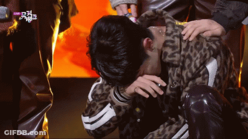 A Man In A Leopard Print Jacket Is Kneeling Down With His Head In His Hands GIF
