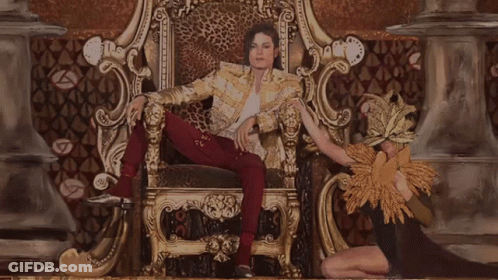 A Man In A Leopard Print Jacket Is Sitting On A Gold Throne GIF