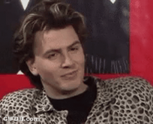 A Man In A Leopard Print Shirt Is Sitting On A Red Couch And Making A Funny Face . GIF