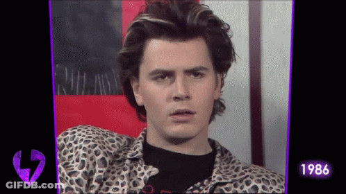 A Man In A Leopard Print Shirt Looks At The Camera With The Year 1986 On The Bottom GIF