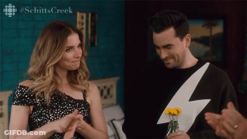 A Man In A Lightning Bolt Sweater Holds A Vase Of Yellow Flowers GIF