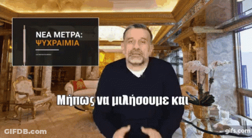 A Man In A Living Room With A Sign That Says " Nea Metpa " GIF